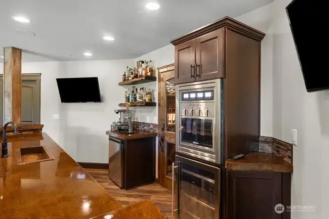 Resort-style estate entertaining at its finest. This high-end custom bar showcases stunning lacquered concrete countertops, built-in sink, wine dispenser, beverage refrigerator, kegerator with beer taps, and commercial ice maker — all designed for effortless hosting and upscale gatherings.