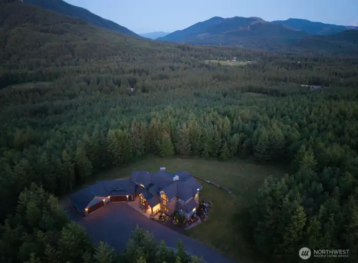 A breathtaking aerial view of this private 10-acre Ravensdale estate, surrounded by lush evergreens and rolling foothills. Tucked into nature with expansive territorial views, this custom home offers rare seclusion, usable land, and endless possibilities for equestrian amenities, a shop, pool, or future expansion. A true Pacific Northwest retreat.