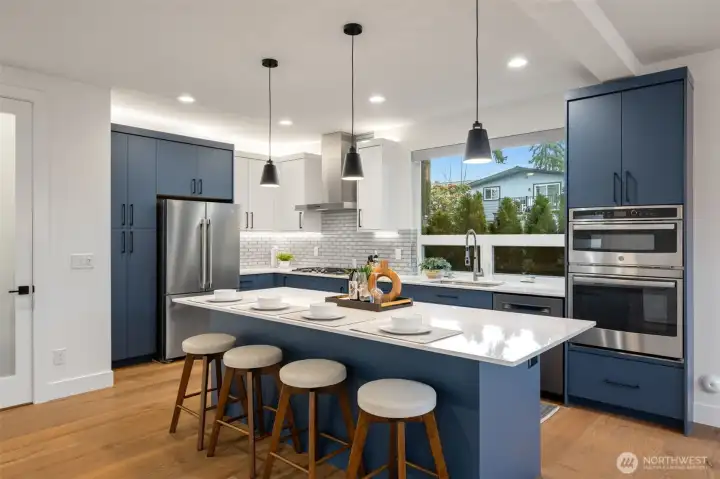 A wow kitchen with quartz counter tops, glass tile backsplash, massive storage space and just to the left- the door goes the walk-in pantry space.