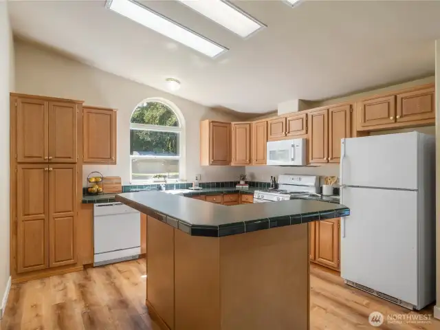 The kitchen features wood cabinets, white appliances, and a center island/eating bar.