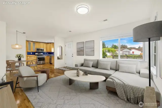 The open concept living room has oak floors and a space for a dining table just off the kitchen.