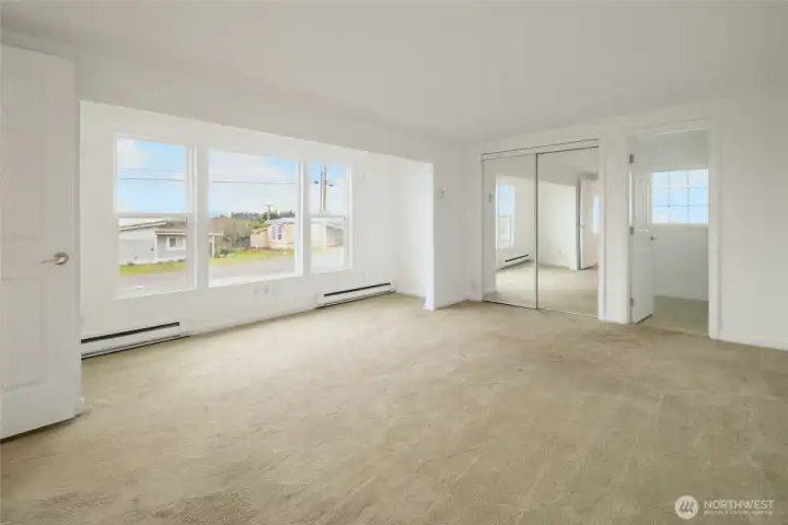 Primary bedroom with spacious closet background middle with entry to ensuite entry on right.