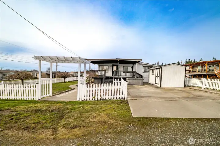 Welcome to 8471 Willow Way primary driveway entry iew with covered viewing deck/porch, hot tub and garden shed