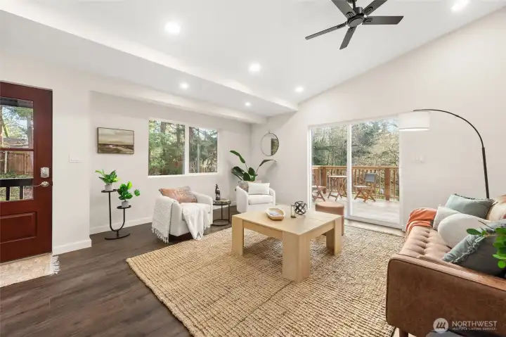 Living room with sliders to front deck. Vaulted ceiling with tons of lighting.