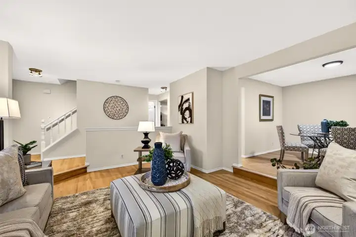 The living room's generous layout and open connection to both the entry and dining area create a natural gathering space where the flow of the home truly shines — hardwood floors, fresh paint, and abundant natural light make this a space that feels both polished and livable.