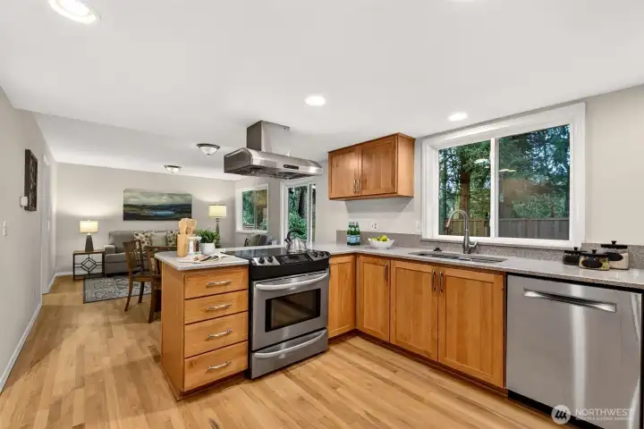 The thoughtfully designed kitchen opens directly to the main living areas, offering stainless steel appliances, warm cabinetry, quartz countertops, and new recessed lighting — a setup that makes everyday cooking and casual entertaining equally effortless.