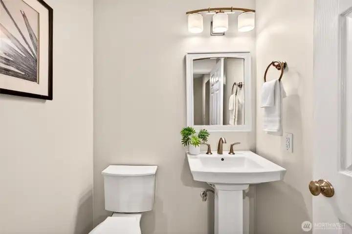 The convenient main level half bath is tastefully appointed with a pedestal sink, brushed gold fixtures, heated floors, and updated lighting — a polished detail that makes a strong impression on guests without sacrificing an inch of practicality.