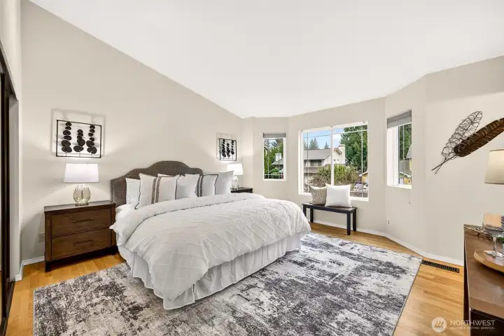 The generous primary suite offers a true retreat with refinished hardwood floors, fresh neutral paint, vaulted ceilings, and a wall of windows that fill the room with natural light and peaceful neighborhood views — a space designed for genuine rest and relaxation.
