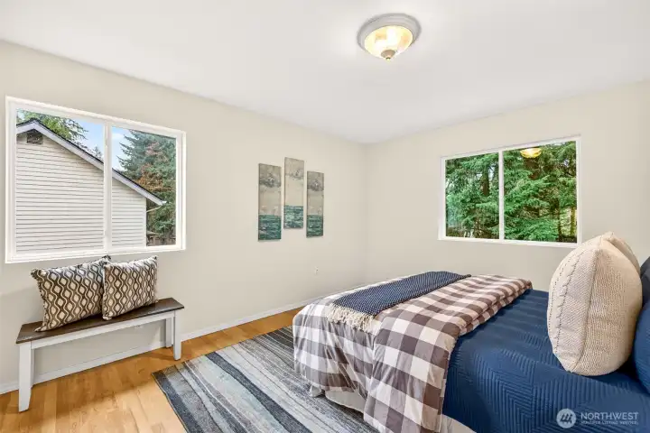 Corner windows on two walls flood this upper level bedroom with natural light and treetop views, creating an airy, private space with hardwood floors and fresh paint that is ready to serve whatever purpose you need most.