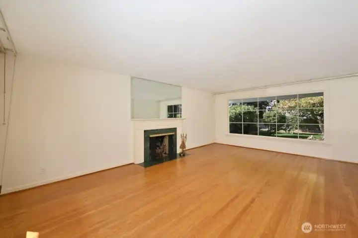 Gleaming oak hardwood floor in living room with gas fireplace and huge window to the rear yard. Looking west south west.