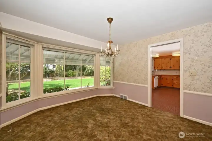 Large Dining Room with another wall of windows to enjoy the backyard greenery view. Those carpets are covering the oak hardwood flooring.  Kitchen is through the door.