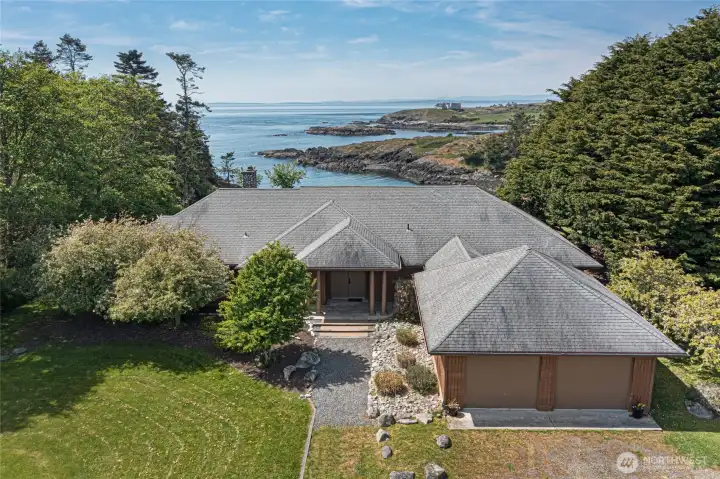 From above, the home's distinctive multi-gabled roofline and warm cedar siding harmonize effortlessly with the coastal landscape, while panoramic ocean views stretching toward the distant mountain ranges set the stage for extraordinary everyday living.