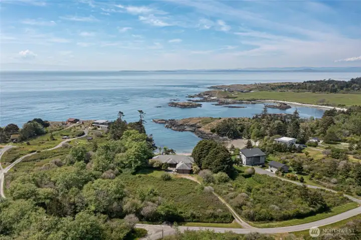Sweeping aerial perspective reveals the breathtaking setting of this San Juan Island retreat, where a protected cove with crystalline blue-green waters frames the property against an endless open-water horizon. Rocky outcroppings, lush greenery, and neighboring waterfront estates set the tone for the coveted island lifestyle awaiting you here.