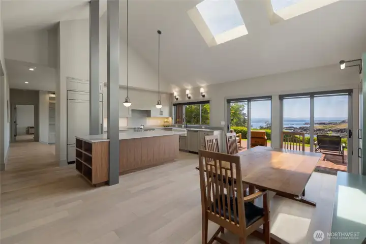 The brand-new chef's kitchen and open-concept dining area soar under dramatic vaulted ceilings with twin skylights, seamlessly connecting to the waterview deck through expansive sliding glass doors. Custom cabinetry, a substantial island, and premium finishes make this the true heart of this island home.