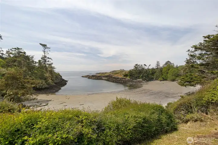 A secluded sandy cove nestled among wind-sculpted firs offers a private retreat accessible from the property, with tidal flats and sheltered waters perfect for kayaking, beachcombing, or simply soaking in the serenity of San Juan Island living.