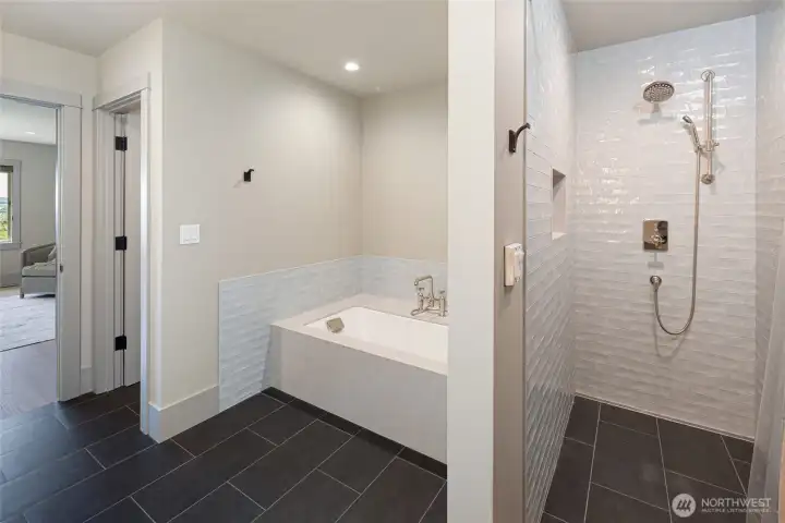 Indulge in the elegance of the primary en-suite bath, complete with a deep soaking tub adorned with polished nickel bridge faucets, handcrafted subway tile surrounds, and a generous walk-in shower — every detail designed for ultimate relaxation.