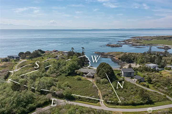 An annotated aerial view showcases the generous footprint of this Kanaka Bay property, with compass orientation highlighting the prime south-facing exposure that bathes the home and grounds in natural light throughout the day. The sheltered cove just steps away offers calm, protected waters ideal for kayaking, swimming, and peaceful waterfront living.