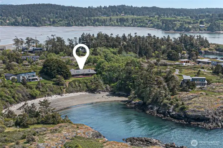The location marker reveals just how intimately this property embraces its own private sandy cove, with the home nestled into the treeline directly above the beach for effortless access to the water's edge. Turquoise tidal waters, driftwood-strewn sands, and sweeping views of the surrounding island landscape make every day feel like a coastal escape.