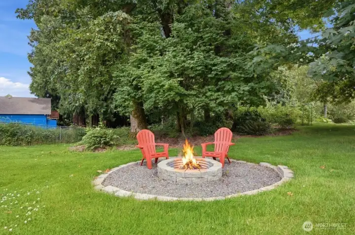 Fire pit on the 1/2 an acre lot with plenty of trees.