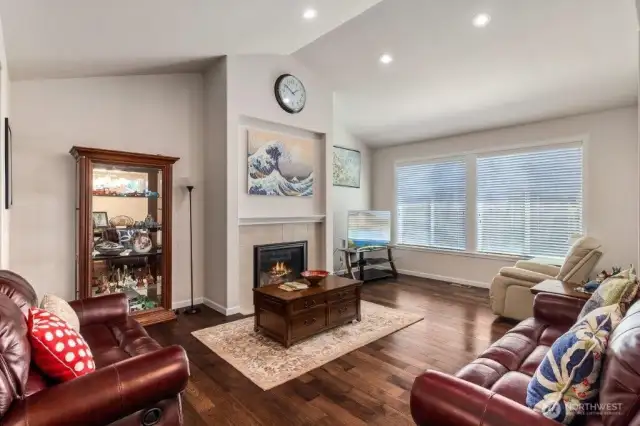 The living room is light and bright with custom blinds and a tall vaulted ceiling.