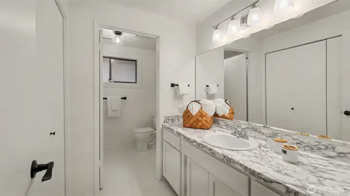 A bright and refreshed guest bath featuring a spacious vanity and a separate water closet for added privacy.