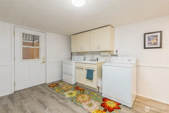 Generous basement laundry room with ample storage, utility sink, and convenient exterior access.