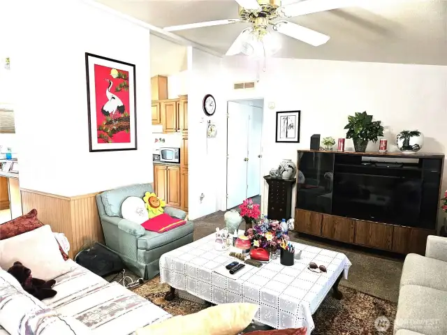 Living room features vaulted ceiling, ceiling fan ans newer carpet.