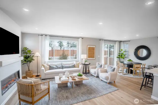Bright and airy open-concept living and dining area featuring a sleek linear electric fireplace and large windows that flood the space with natural light.
