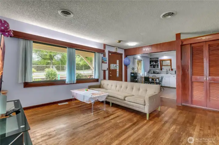 Open living room with original hardwood floors that flows seamlessly into the kitchen with a convenient eating space.