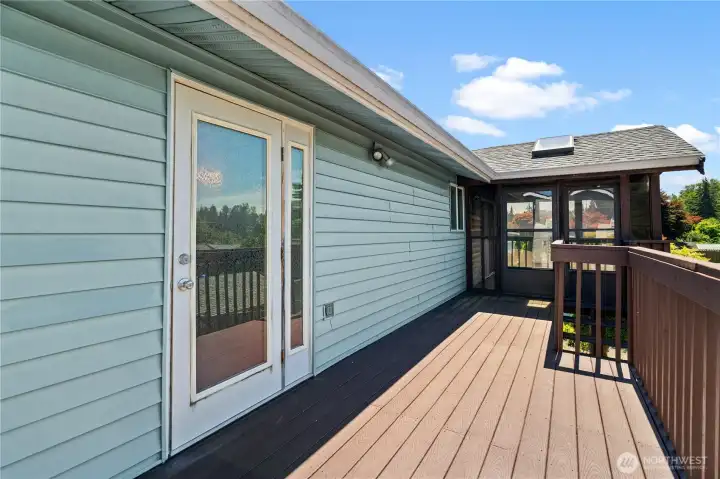 Deck looking from 2nd floor storage towards primary bedroom (in foreground) and enclosed deck off dining and kitchen