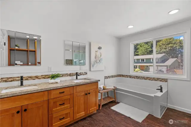 En-suite bathroom features updated vanity, sizable bathtub, large window, recessed light, and plenty of storage.