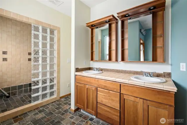Primary bath features a double sink and full glass block shower.