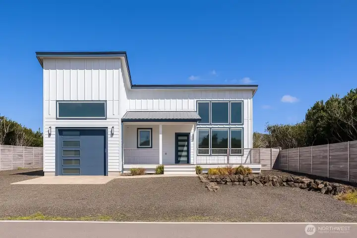 Sophisticated modern coastal home with floor to ceiling windows, covered front porch and extra deep garage