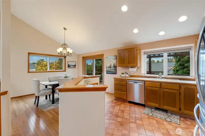 The kitchen flows seamlessly into the dining area, where large windows and sliding glass doors frame views of mature trees and the huge backyard. Perfect for casual meals or gatherings.