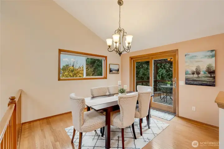 Light-filled dining area with vaulted ceilings, hardwood floors, and sliding glass doors that open to the deck. A perfect gathering space for everyday meals or entertaining guests.