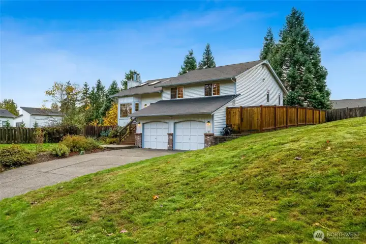Gently sloped front yard adds dimension and privacy while showcasing the home’s two-car garage, inviting exterior, and classic Northwest architecture.