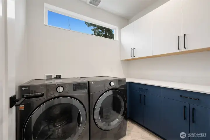 Great laundry room with storage and quartz countertops.
