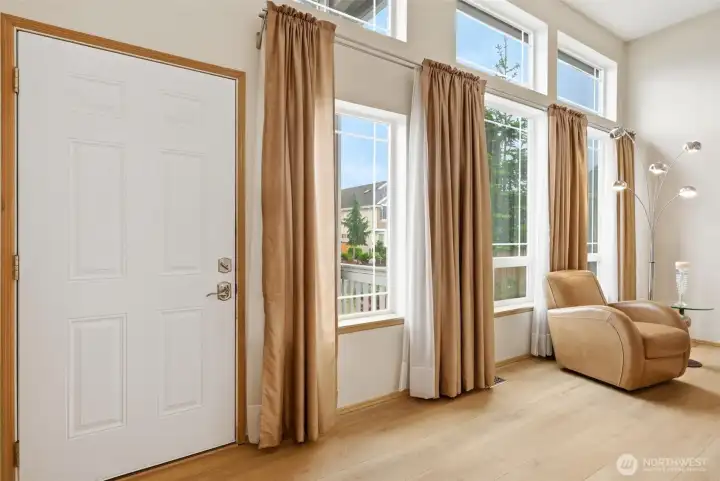 The inviting front door opens to a light-filled family room featuring expansive windows and abundant natural light.