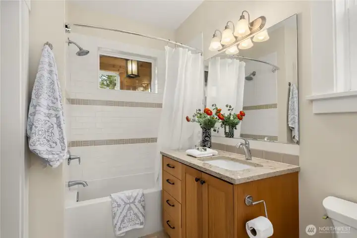A deep soaking tub with a tile surround and granite topped vanity with Kohler fixtures.