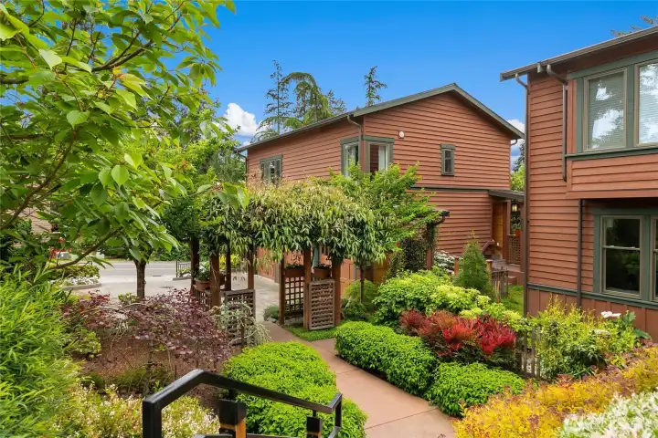 From the top of the steps and facing South East, you can see the main entrance with a Wisteria laden arbor,  another privately owned home to the right and the entrance to Subject Property just between the two.