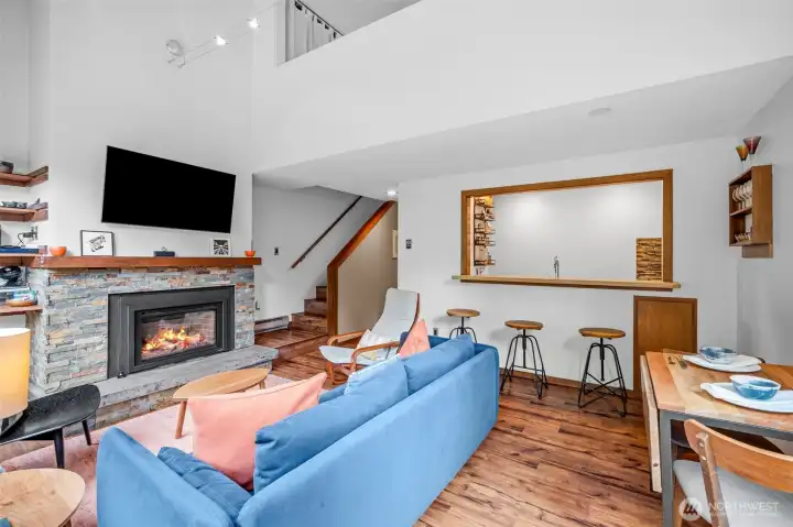 Kitchen eating bar with three barstools and stairs leading to upper level.