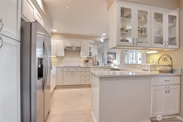 Well appointed kitchen with granite countertops, stainless appliances, solid surface plank flooring and display cabinets
