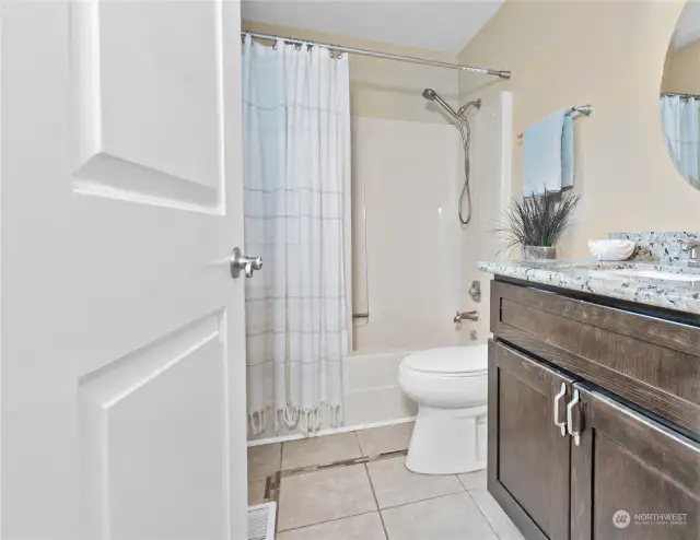 Shared full bathroom with tiled floors, a single sink and ample storage behind the entry door.