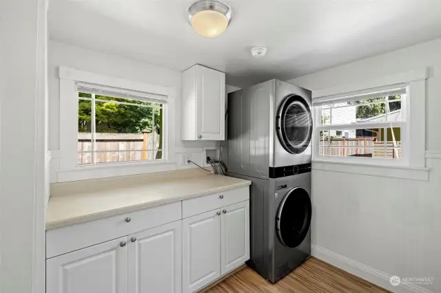 HUGE laundry room with folding counter, storage and new full sized washer/dryer combo.