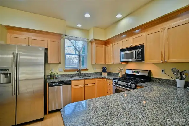 Sizeable kitchen with beautiful maple cabinets, expansive granite countertops, stainless steel appliances, large peninsula with a breakfast bar seating, maple hardwood floors and a door with access to the back deck.