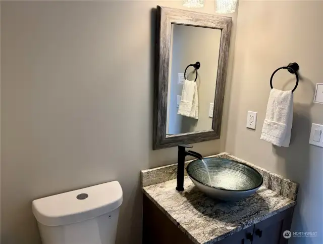 Elegant powder room features Vessel sink with waterfall faucet.