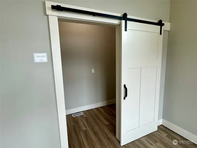 barn door opens to a walk-in closet