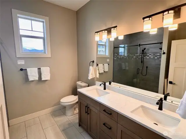 Primary suite offers this beautiful bathroo offering tile floor, double vanity with stunning black faucets.