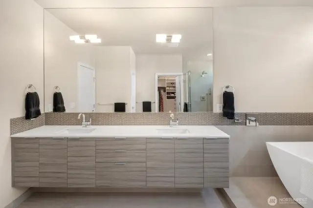 The primary bath's floating vanity and double, undermounted sinks are in the foreground, and the nice, big, walk-in closet is in the reflection