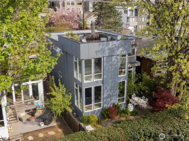 From above and behind, here is a photo of this iconic home, showing the rooftop deck living space, shown nestled among the trees and the gorgeous private garden
